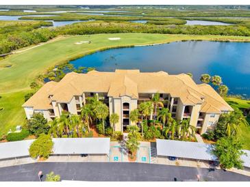 Stunning aerial view of the condo with golf course, lake, and parking; beautiful grounds with lush tropical landscaping at 7705 Grand Estuary Trl # 202, Bradenton, FL 34212