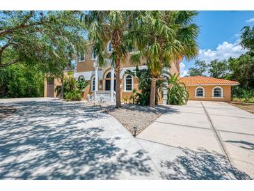 Two-story tan home with a spacious driveway, palm trees, and decorative white lion statues at 95 Vic Edwards Rd, Sarasota, FL 34240