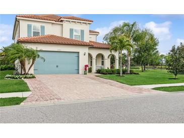 Charming two-story home featuring a brick driveway, a teal garage door, and a well-manicured lawn at 13721 Saw Palm Creek Trl, Lakewood Ranch, FL 34211