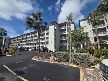 Exterior view of a condo complex showing multiple balconies, palm trees and well-maintained landscaping at 3368 Lake Bayshore Dr # 217 Building P, Bradenton, FL 34205