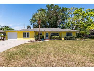 Charming yellow single-story home featuring a well-manicured lawn and a mature palm tree in the front yard at 337 Somerset Ave, Sarasota, FL 34243