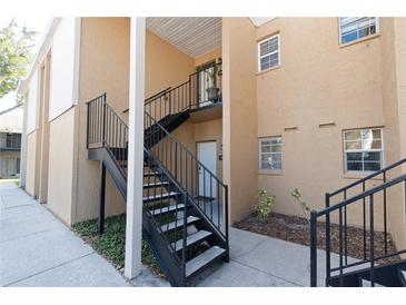 Exterior view of a tan condo building with black metal stairs and walkway leading to each unit at 3810 N Oak Dr # N61, Tampa, FL 33611