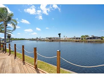 Scenic waterfront view from a wooden deck, showcasing the tranquil canal and neighboring homes under a clear sky at 520 Ideal Pl, North Port, FL 34287