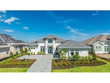 Beautiful home with a grey brick driveway, tropical landscaping, and grey shingled roof at 600 Blue Shell Loop, Sarasota, FL 34240