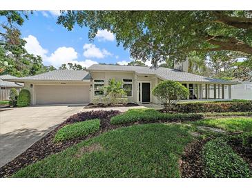 Charming home featuring a lush, well-manicured front yard with mature trees and landscaping at 1046 Greystone Ln, Sarasota, FL 34232