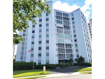 Stunning exterior shot of a white condo building, showcasing lush landscaping and an American flag at 435 S Gulfstream Ave # 605, Sarasota, FL 34236