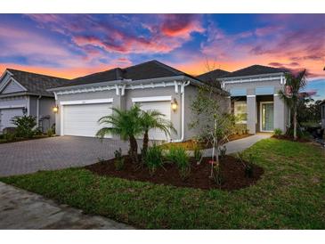 Beautiful single-story home with a two car garage, lush landscaping and a paver driveway at sunset at 10217 Canaveral Cir, Sarasota, FL 34241