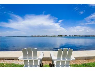 Relaxing waterfront view with two white Adirondack chairs on the water at 117 7Th N St # 5, Bradenton Beach, FL 34217