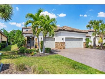 Beautiful home with a tile roof, manicured landscaping, brick driveway, and a three-car garage at 13902 Messina Loop, Bradenton, FL 34211