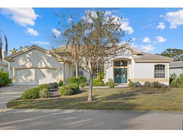 Charming home featuring stucco siding, manicured landscaping, and a welcoming double-door entrance with decorative wreaths at 5449 Downham Mdws, Sarasota, FL 34235