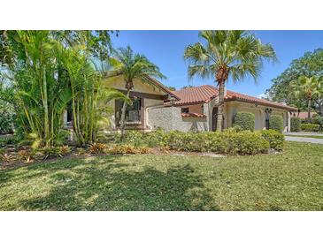 Exterior view of home featuring lush landscaping, a tiled roof, and a well-maintained lawn at 5458 Golf Pointe Dr, Sarasota, FL 34243