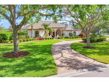 Charming single-story home featuring a well-manicured lawn, beautiful landscaping, and a circular brick driveway at 7408 S Serenoa Dr, Sarasota, FL 34241