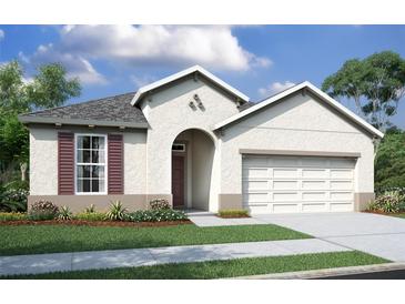 Charming single-story home featuring a stucco facade, arched entryway, two-car garage, and manicured front lawn at 19679 Fort King Run, Brooksville, FL 34601