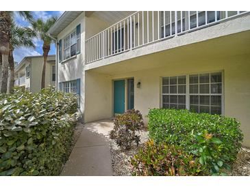 Inviting condo exterior featuring a walkway, manicured shrubbery, and a private balcony with white railings at 208 Silver Lake Dr # 101, Venice, FL 34292