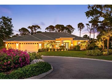 Inviting single-story home featuring a three-car garage, lush landscaping, and charming curb appeal at twilight at 2196 Muskogee Trl, Nokomis, FL 34275