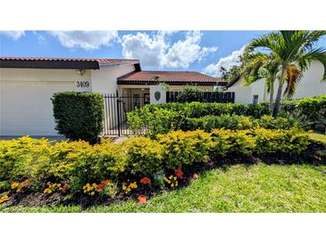 Charming single-story home features a well-manicured lawn, blooming flowerbeds, and black gated front porch at 3409 Montilla Ct # 8410, Sarasota, FL 34232