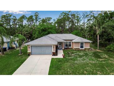 Inviting single-story home with a gray roof, attached garage, and lush green surroundings at 4673 Lummus St, North Port, FL 34286
