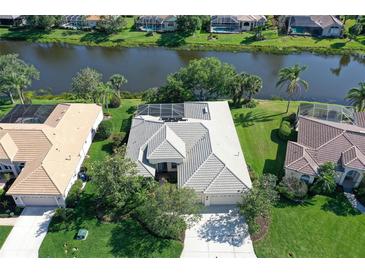 This aerial view showcases a lovely single-story home with a tile roof and screened-in lanai overlooking a serene waterway at 5032 Timber Chase Way, Sarasota, FL 34238