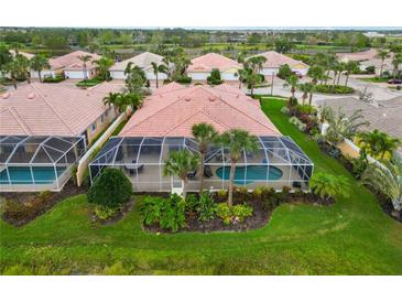 An aerial view of a tile-roofed home featuring a screened-in pool and lush, green landscaping in a tropical neighborhood at 6209 Erice St, Venice, FL 34293