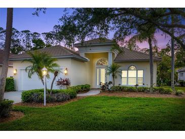 Charming single-story home showcasing lush landscaping, an arched entryway, and a welcoming two-car garage at 7016 Lennox Pl, University Park, FL 34201