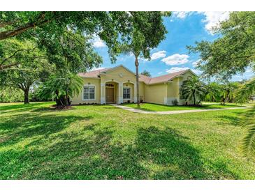 Inviting single-story home featuring a lush lawn, mature trees, and charming curb appeal under a blue sky at 8136 Snowy Egret Pl, Bradenton, FL 34202
