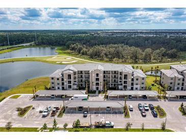 An aerial view of the condos with covered parking, green space, lake and golf course in the background at 18114 Gawthrop Dr # 306, Bradenton, FL 34211
