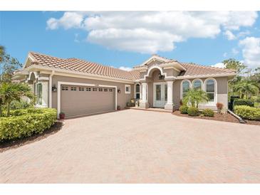 Charming single-story home featuring a tile roof, brick driveway, and well-manicured landscaping at 5480 White Ibis Dr, North Port, FL 34287