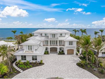 Gorgeous waterfront home showcasing lush landscaping, a brick driveway, and stunning architectural details at 619 Key Royale Dr, Holmes Beach, FL 34217