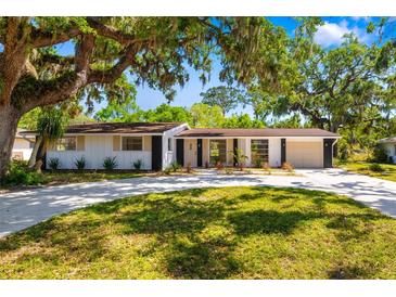Charming single-story home with mature trees, well-manicured lawn, and a long driveway at 7158 S Leewynn Dr, Sarasota, FL 34240