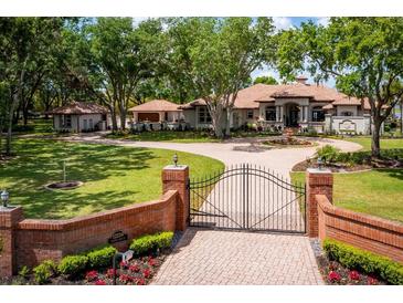 Stately home featuring a gated entrance, circular driveway, and lush landscaping, offering curb appeal and privacy at 12224 Garden Lake Cir, Odessa, FL 33556