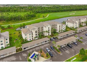 An aerial view showcasing the condo building, golf course, parking, and verdant greenery at 18028 Gawthrop Dr # 406, Bradenton, FL 34211