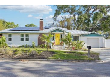 Charming home with a bright yellow door, brick chimney, solar panels, and beautifully landscaped front yard at 2216 13Th W Ave, Bradenton, FL 34205