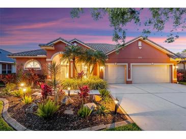 Charming home featuring well-manicured landscaping, a tile roof, and a two-car garage at dusk at 4926 Sabal Lake Cir, Sarasota, FL 34238