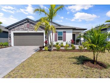 Charming single-story home with stone accents, a paver driveway, and meticulously landscaped front yard with manicured lawn at 5317 Patano Loop, Palmetto, FL 34221