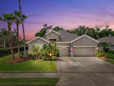 Charming home showcasing a well-manicured lawn, lush landscaping, and a welcoming three-car garage at dusk at 5907 90Th Avenue E Cir, Parrish, FL 34219