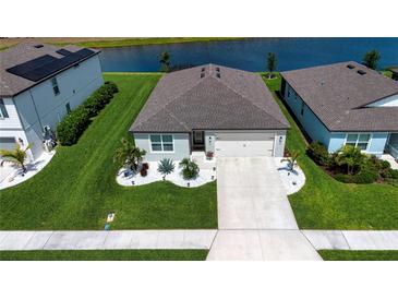 Beautiful single-Gathering home with a two-car garage, well-manicured lawn, and elegant landscaping near lake at 8232 Reefbay Cv, Parrish, FL 34219