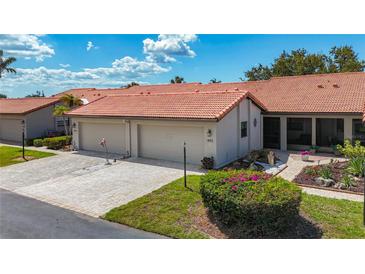 Charming single-story villa with a tile roof, attached garage and walkway leading to the covered screened porch at 892 Country Club Cir # 50, Venice, FL 34293