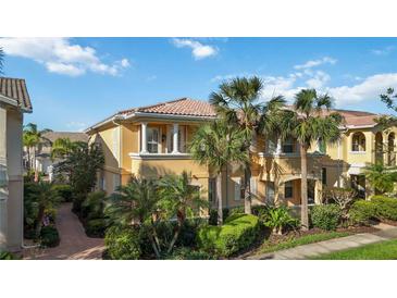 Beautiful two-story townhouse with lush landscaping, palm trees and classic architectural detailing on a sunny day at 1586 Dorgali Dr, Sarasota, FL 34238
