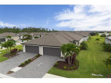 Beautiful new construction home featuring a three car garage, paver driveway, and lush tropical landscaping at 2193 Bonito Way, Port Charlotte, FL 33953