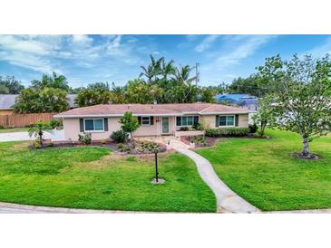 Charming single-story home with well-maintained lawn and tropical landscaping under a sunny, partly cloudy sky at 3072 Meyer Dr, Sarasota, FL 34239