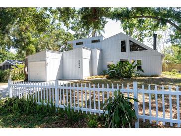 Charming home featuring unique architecture, a white picket fence, and mature landscaping at 4639 Sloan Ave, Sarasota, FL 34233