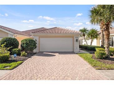 Charming home exterior featuring a brick driveway, two car garage, lush landscaping, and tile roof at 5509 Avellino Pl, Sarasota, FL 34238