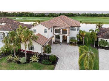 Stunning two-story waterfront home with a tile roof, landscaped yard and a brick driveway at 5609 Arnie Loop, Lakewood Ranch, FL 34211