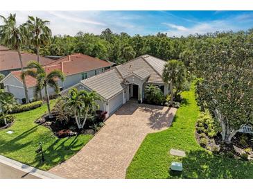 Beautiful single-story home with a tile roof, brick driveway, mature landscaping, and a two-car garage at 643 Misty Pond Ct, Bradenton, FL 34212