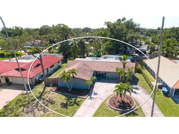 A charming single-Gathering home with a circular driveway is surrounded by lush landscaping and mature palm trees at 7019 10Th S St, St Petersburg, FL 33705