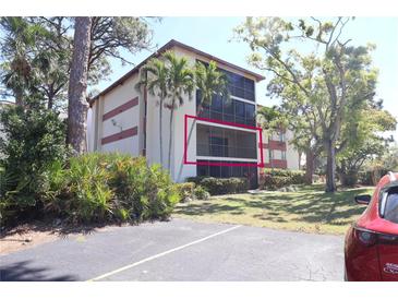 Low-angle daytime view of a condo with a screened balcony bordered in red and surrounded by trees and other greenery at 7500 40Th W Ave # 209, Bradenton, FL 34209