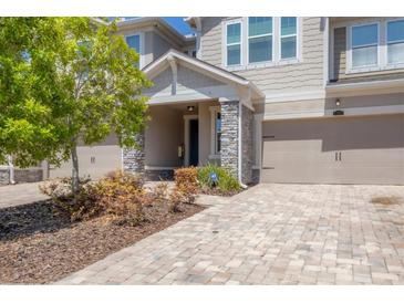 Charming townhome with stone accents, a welcoming front porch, and a brick-paved driveway at 11925 Brookside Dr, Bradenton, FL 34211