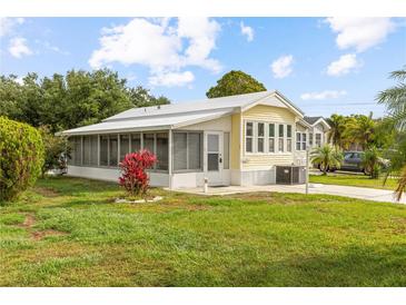 Charming yellow home with a screen porch, green lawn and colorful foliage in a sunny setting at 182 Crown Point Dr, Nokomis, FL 34275