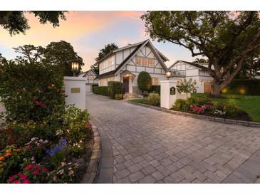 Charming two-story home with Tudor details, beautiful landscaping, and a paved driveway leading to the garage at 1829 Bougainvillea St, Sarasota, FL 34239