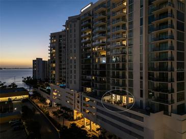 Exterior view of the high-rise building showing a private outdoor patio with furniture and the city in the background at 301 Quay Commons # 507, Sarasota, FL 34236